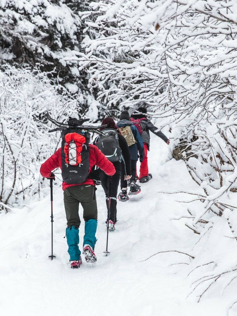 2 person in red jacket and black pants standing on snow covered ground during daytime